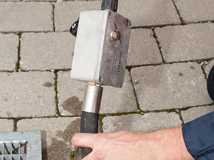 Dichtheitsprüfung am Straßenkanal Techniker von PAKO führt eine Dichtheitsprüfung an einem Straßenkanal durch, mit Messeinrichtung am Schacht