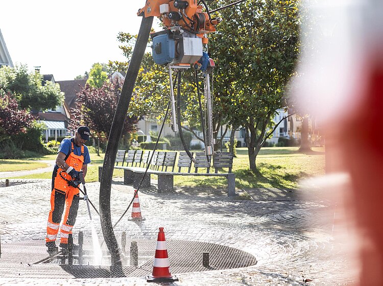 Spülarbeiten auf Baustelle PAKO-Mitarbeiter bei Spülarbeiten auf einer Baustelle, Wasser wird mit Hochdruck eingesetzt, Umgebung teilweise unscharf.