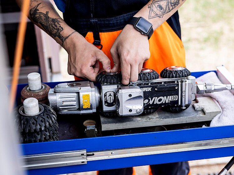 TV-Inspektion mit Fahrwagenkamera PAKO-Mitarbeiter führt eine TV-Inspektion mit einer Fahrwagenkamera an einem geöffneten Schacht durch.