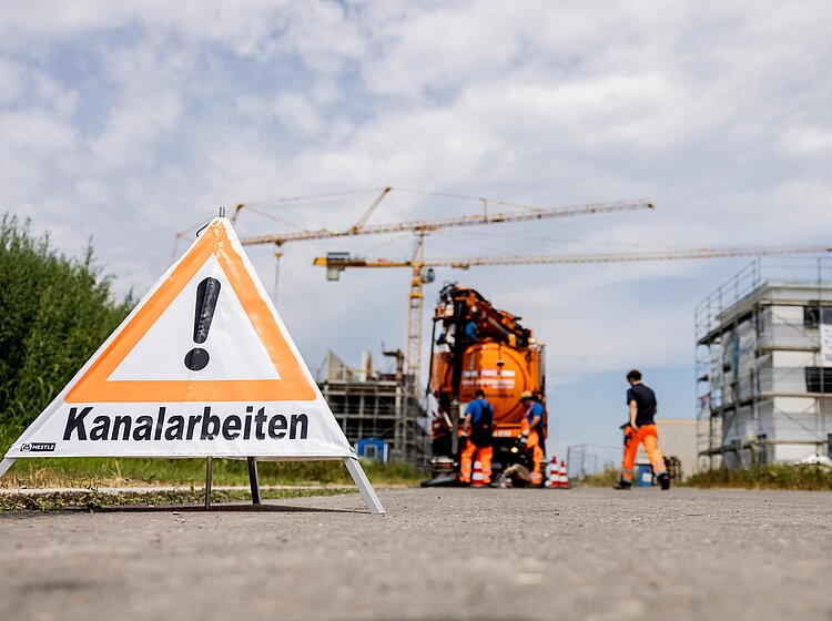 Baustelle mit PAKO-Fahrzeug PAKO-Fahrzeug auf einer Straße im Einsatz, davor ein Baustellenschild mit Warnhinweis und Absperrung.