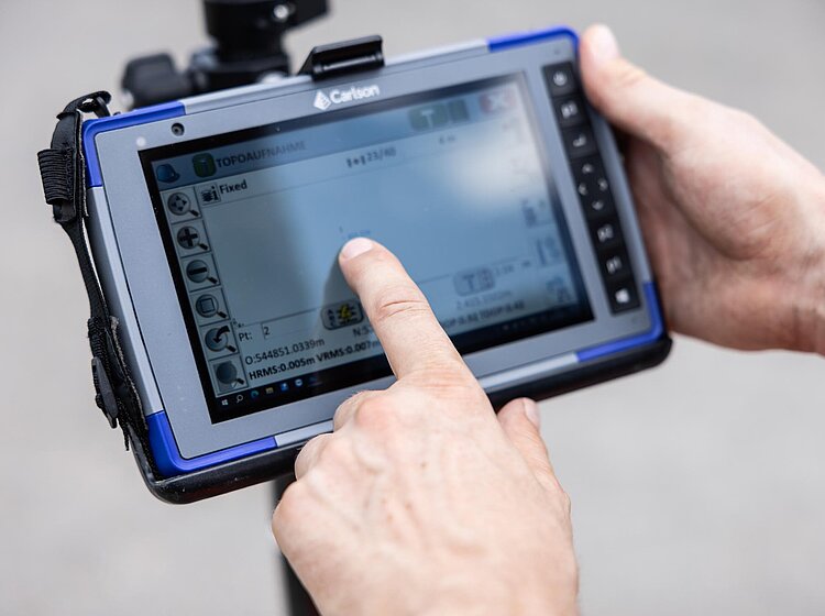 Tablet bei Kamerainspektion Zwei Hände bedienen ein Tablet mit Livebild einer Rohrkamera während einer Inspektion.