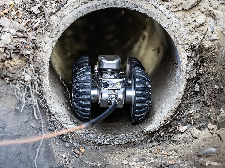 Kamerafahrt in Betonrohr Fahrwagenkamera fährt durch ein großes Betonrohr für eine TV-Inspektion, Kabel und Kamera gut erkennbar.