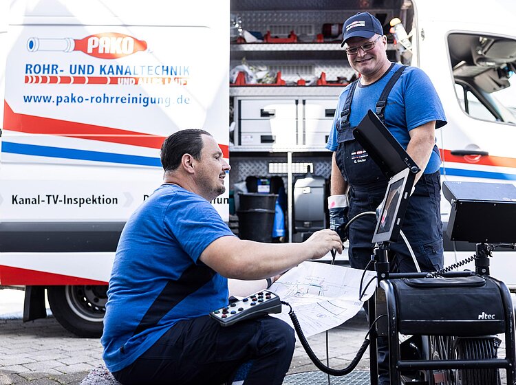 PAKO-Team bei der Kanal-TV-Inspektion Zwei PAKO-Mitarbeiter bei der Vorbereitung einer Kanal-TV-Inspektion vor einem Servicefahrzeug