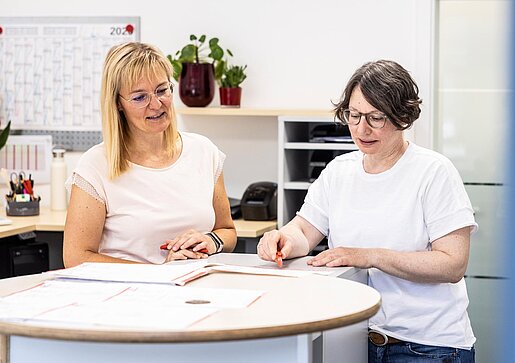 Beratung am Empfang Zwei Mitarbeiterinnen der PAKO Rohr- und Kanaltechnik GmbH & Co. KG stehen an einem Empfangstresen und besprechen Unterlagen.