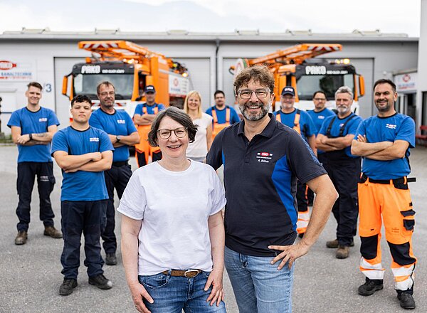 Teamfoto mit Fhrungskräften PAKO-Mitarbeiter und Führungskräfte stehen gemeinsam auf dem Hof und lächeln.