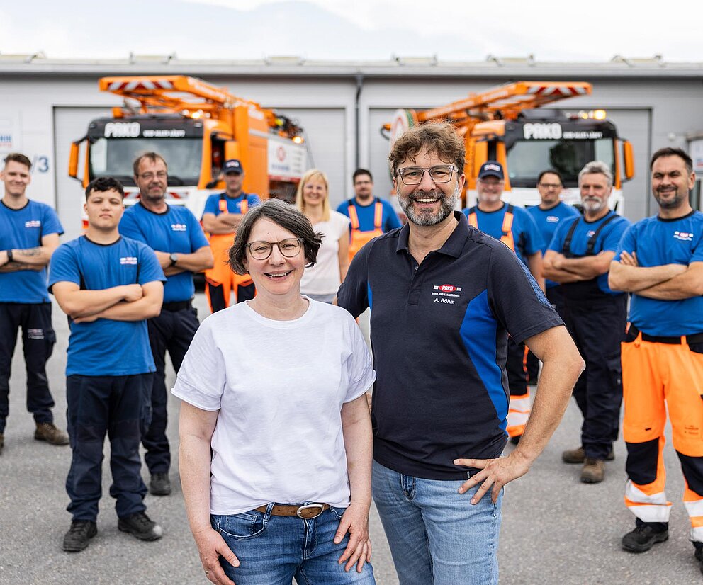 Teamfoto mit Fhrungskräften PAKO-Mitarbeiter und Führungskräfte stehen gemeinsam auf dem Hof und lächeln.