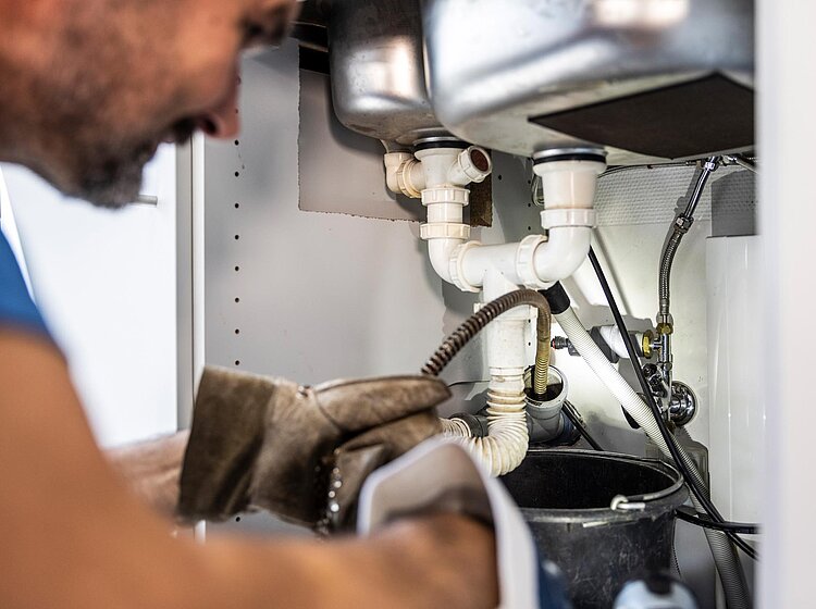 Rohrreinigung in der Küche PAKO-Mitarbeiter bei der Rohrreinigung unter einer Küchenspüle mit professionellem Werkzeug