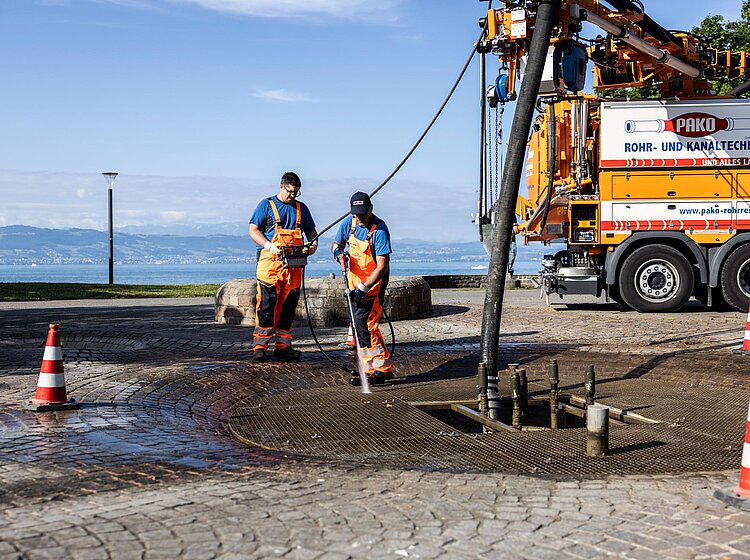 Straßenarbeiten mit Saugbagger PAKO-Team führt Saugbagger-Arbeiten an einer geöffneten Straße durch, mehrere Mitarbeiter vor Ort.