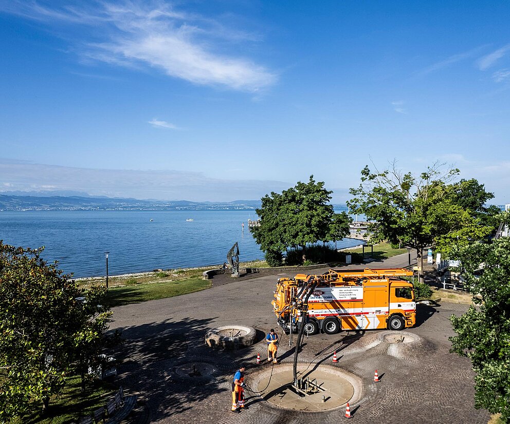 PAKO-Fahrzeug am Seeufer PAKO-Servicefahrzeug steht an einem Ufer mit Blick auf einen See und grüne Hügel.