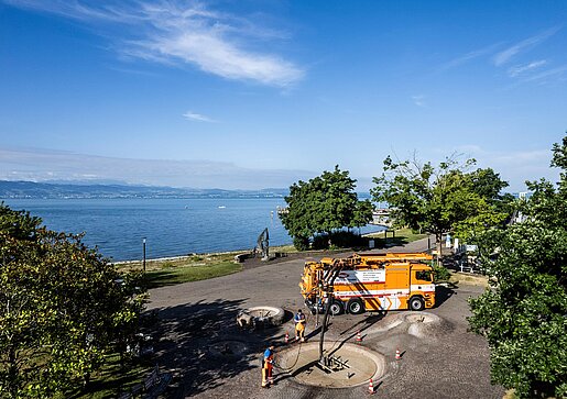 PAKO-Fahrzeug am Seeufer PAKO-Servicefahrzeug steht an einem Ufer mit Blick auf einen See und grüne Hügel.