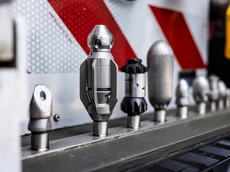 Düsen für Hydrodynamische Reinigung Verschiedene Reinigungsdüsen zur hydrodynamischen Rohrreinigung ordentlich aufgereiht in einem Fahrzeug oder Werkstattbereich.