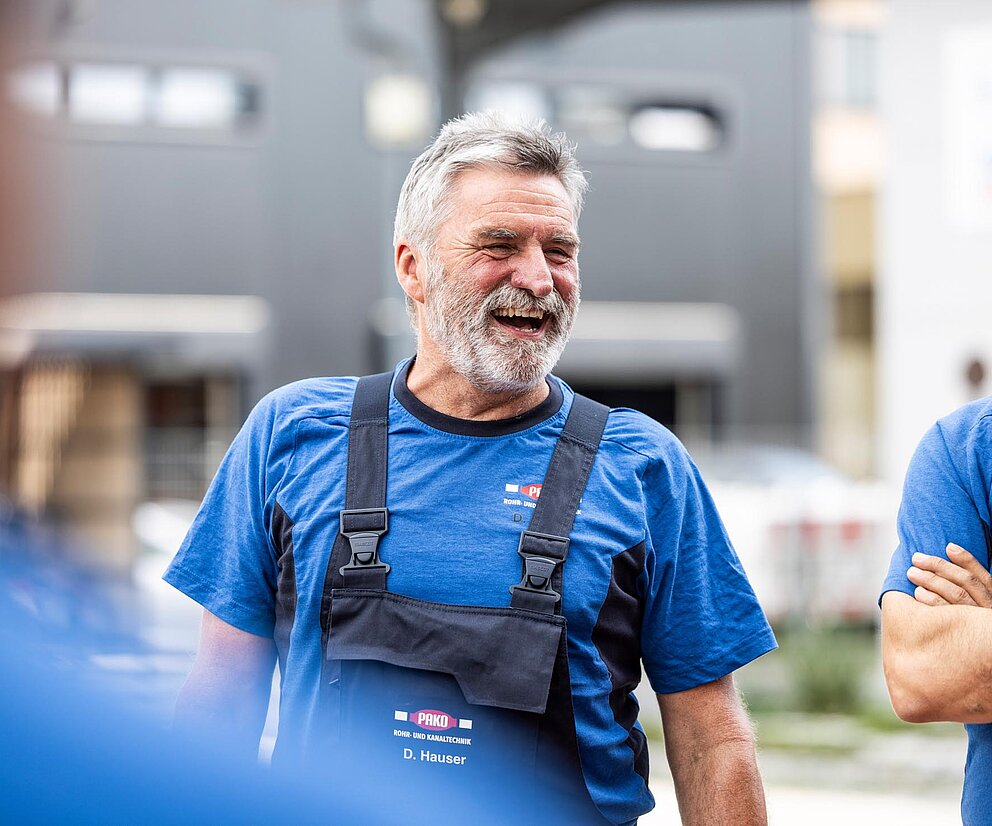 Mitarbeiter bei der Arbeit Zwei PAKO-Mitarbeiter in blauer Arbeitskleidung lachen während einer Besprechung in der Werkstatt.