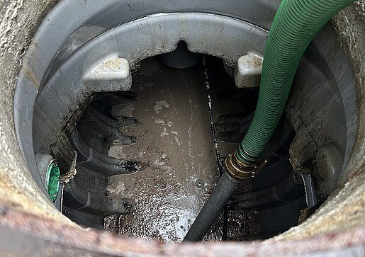 Fettabscheider-Reinigung durch PAKO Reinigung eines Fettabscheiders durch PAKO mit grünem Absaugschlauch im geöffneten Schacht