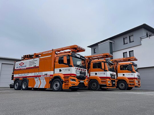 PAKO-Spezialfahrzeuge auf Betriebshof Zwei orangefarbene Spezialfahrzeuge der PAKO Rohr- und Kanaltechnik GmbH & Co. KG vor dem Firmengebäude auf dem Hof geparkt.