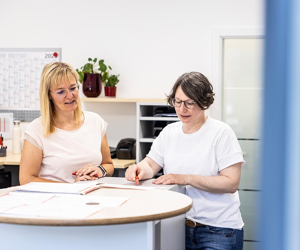Beratung am Empfang Zwei PAKO-Mitarbeiterinnen besprechen Unterlagen am Empfangstresen im Büro.